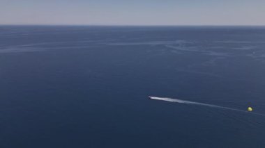 Bir tekneye bağlı paraşütle uçmanın havadan izlenen su sporları eğlencesi. Ekstrem yaz sporları plaj turizmi. Yüksek kalite 4k dikey görüntü. 