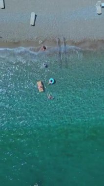 Parlak güneşli bir günün havadan görünüşü tropikal tatil beldelerini aydınlatıyor. İnsanlar plajda yüzerken ve şemsiyeyle güneşlenirken gördü. Türkiye 'deki sahil turist beldeleri