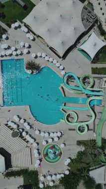 Güneşli yaz günlerinde güneşlenmeyi ve dinlenmeyi, mavi su havuzlarında yüzmeyi, havadan çekim yapmayı seven insanların en iyi görüntüsü. Yüksek kalite 4k dikey görüntü