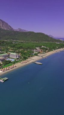 Parlak güneşli bir günün havadan görünüşü tropikal tatil beldelerini aydınlatıyor. İnsanlar plajda yüzerken ve şemsiyeyle güneşlenirken gördü. Türkiye 'deki sahil turist beldeleri