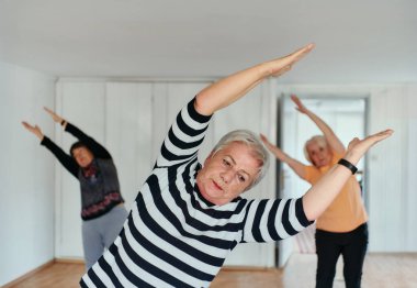 Bir grup son sınıf öğrencisi, güneş alan bir alanda eğitmenin rehberliğinde boyun, sırt ve bacak esnetme gibi çeşitli yoga egzersizleri yaparak refahı ve uyumu sağlıyorlar.. 