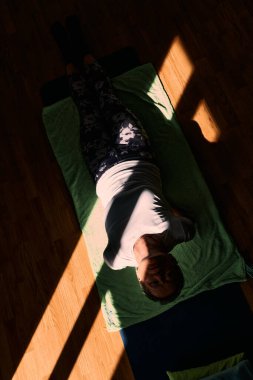 An elderly woman engages in a stretching and meditation session on the floor, concentrating on alignment and mindful relaxation. clipart