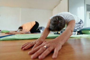 Bir grup son sınıf öğrencisi, güneş alan bir alanda eğitmenin rehberliğinde boyun, sırt ve bacak esnetme gibi çeşitli yoga egzersizleri yaparak refahı ve uyumu sağlıyorlar.. 