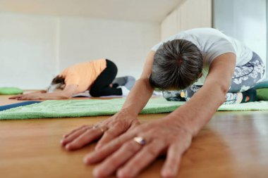 Bir grup son sınıf öğrencisi, güneş alan bir alanda eğitmenin rehberliğinde boyun, sırt ve bacak esnetme gibi çeşitli yoga egzersizleri yaparak refahı ve uyumu sağlıyorlar.. 