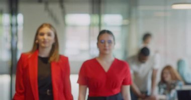 Kendine güvenen iş kadınlarından oluşan bir ekip modern bir başlangıç sahasının koridorlarında yürürken çapraz kollarla kendilerini işe adadıklarını gösteriyorlar.
