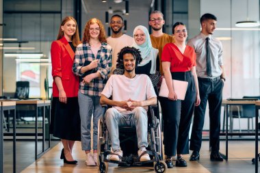 A diverse group of young business people walking a corridor in the glass-enclosed office of a modern startup, including a person in a wheelchair and a woman wearing a hijab. clipart