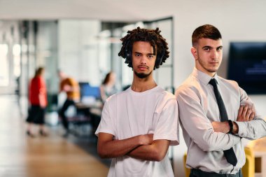 Aralarında Afro-Amerikalı bir işadamı ve gömlek ve kravat takmış genç bir liderin de bulunduğu bir grup meslektaşı, dinamik bir karışımı temsil eden modern bir çalışma merkezi ofisinde birlikte poz veriyorlar.