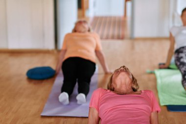 Bir grup son sınıf öğrencisi, güneş alan bir alanda eğitmenin rehberliğinde boyun, sırt ve bacak esnetme gibi çeşitli yoga egzersizleri yaparak refahı ve uyumu sağlıyorlar.. 