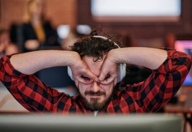 A cheerful man in a coworking space engages in a lively video call, showcasing his excitement and creativity through playful hand gestures. clipart