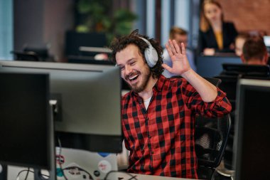 Birlikte çalışan neşeli bir adam, hareketli el hareketleriyle heyecanını ve yaratıcılığını gösteren canlı bir video çağrısına girişir..