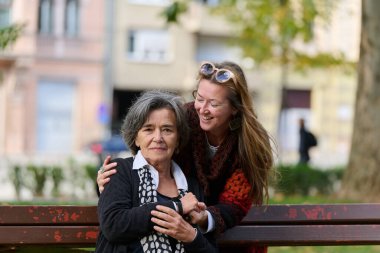 Güzel bir günde, sakin bir parkta, bir kız büyük annesini sevgiyle kucaklıyor, birlikte geçirdikleri güzel bir anı paylaşırken ona destek ve neşe sunuyor..