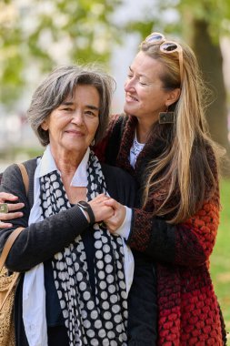 Büyüleyici bir sonbahar gününde, bir kız çocuğu yaşlı annesini sevgiyle kucaklıyor, el ele tutuşuyor ve birlikte huzurlu bir anın tadını çıkarırken sarsılmaz bir destek sunuyor..