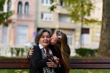 Güzel bir günde, sakin bir parkta, bir kız büyük annesini sevgiyle kucaklıyor, birlikte geçirdikleri güzel bir anı paylaşırken ona destek ve neşe sunuyor..