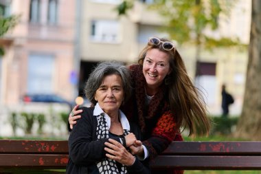 Güzel bir günde, sakin bir parkta, bir kız büyük annesini sevgiyle kucaklıyor, birlikte geçirdikleri güzel bir anı paylaşırken ona destek ve neşe sunuyor..