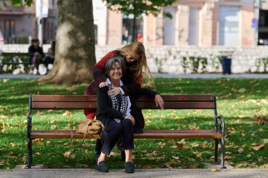 Güzel bir günde, sakin bir parkta, bir kız büyük annesini sevgiyle kucaklıyor, birlikte geçirdikleri güzel bir anı paylaşırken ona destek ve neşe sunuyor..