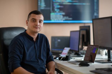 Bir programcı ofisinde otururken akıllı telefon uygulamalarını özenle test ediyor. Yüksek kalite fotoğraf
