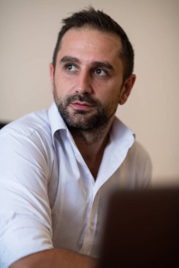 Ofiste otururken akıllı telefonuyla konuşan bir işadamı profesyonel tavrını ve aktif iletişimini gösteriyor.