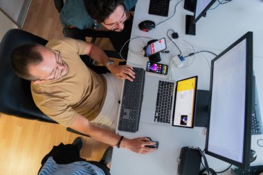 Akıllı telefon uygulamalarını ofisinde otururken özenle test eden programcının üst görünümü