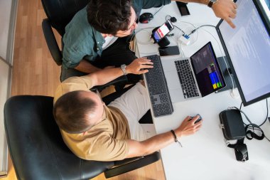Akıllı telefon uygulamalarını ofisinde otururken özenle test eden programcının üst görünümü