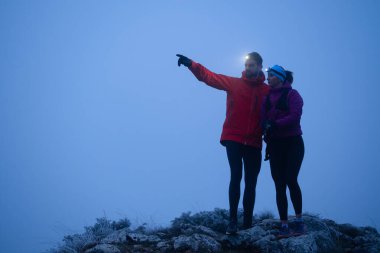 Eğitimden sonra nefes almaktan sıkılan koşucular, teknoloji sporu saatlerine bakmaktan, kalp atış hızı verilerini ve navigasyonlarını kontrol etmekten bıktılar. İki sporcu bir dağda birlikte koşuyor..