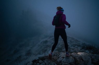 Açık havada egzersiz yapmak aktif yaşam tarzı koşucuları için sağlıklıdır. Sonbahar izleri, doğada koşan bir kadını karanlık ormanda arkadan kovalar. Açık hava koşusu. Yüksek kalite fotoğraf