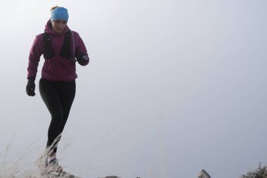Koşan kadın sporcu, dağdaki ultra-maraton yarışına hazırlanıyor. Açık havada antrenman yapan koşucu bir kadın aktif ve zinde bir hayat sürüyor. Siluet sabahın erken saatlerinde.