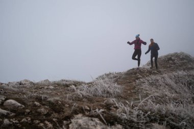 Sabahın erken saatlerinde dağın tepesinde koşan atlet çift patikası. Gökyüzü koşma konsepti, arka planda gökyüzü varken sınırda koşmak tehlikeli. Sağlıklı yaşam, kardiyo egzersizi, spor.