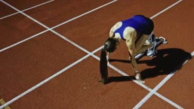 Atletizm atletizm sprint yarışı koşucusu koyu bir arka planda, stadyumun pistinde spor ayakkabılarla koşu koşusuna çıkıyor. Yavaş çekim