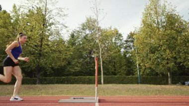 Dişi sporcu bir engele doğru koşuyor, engelli koşuyor, yüksek hızda bariyerin üzerinden atlıyor bir yarışta koşarken. Hız Rampası Efektli Süper Yavaş Sinema Görüntüsü.