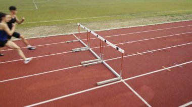 Stadyuma atletik zinde bir çift erkek ve kadın fırlatılıyor. Sıcak bir yaz öğleden sonrasında engellerin üzerinden atlamak. Yavaş Hareket İzleme Görüntüsü. 