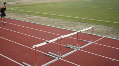 Stadyuma atletik zinde bir çift erkek ve kadın fırlatılıyor. Sıcak bir yaz öğleden sonrasında engellerin üzerinden atlamak. Yavaş Hareket İzleme Görüntüsü. 
