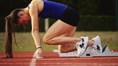 Atletizm atletizm sprint yarışı koşucusu koyu bir arka planda, stadyumun pistinde spor ayakkabılarla koşu koşusuna çıkıyor. Yavaş çekim