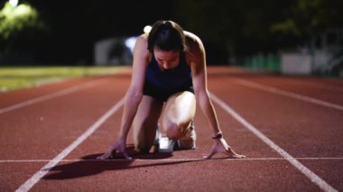 Atletizm atletizm sprint yarışı koşucusu koyu bir arka planda, stadyumun pistinde spor ayakkabılarla koşu koşusuna çıkıyor. Yavaş çekim