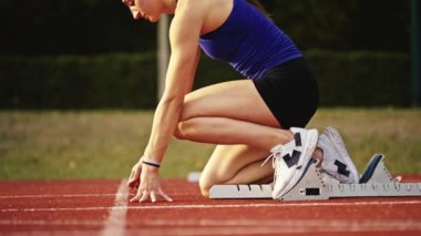 Atletizm atletizm sprint yarışı koşucusu koyu bir arka planda, stadyumun pistinde spor ayakkabılarla koşu koşusuna çıkıyor. Yavaş çekim