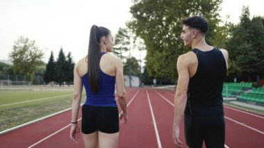 Sportif atletizm çifti stadyumun etrafında koşmayı bitirdi. Spor pistinde dinlenirken yürüyorlar ve keyifli sohbetler ederken nefes alıyorlar. Yüksek kalite 4 bin ağır çekim