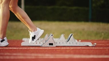 Atletizm atletizm sprint yarışı koşucusu koyu bir arka planda, stadyumun pistinde spor ayakkabılarla koşu koşusuna çıkıyor. Yavaş çekim