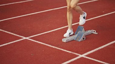 Atletizm atletizm sprint yarışı koşucusu koyu bir arka planda, stadyumun pistinde spor ayakkabılarla koşu koşusuna çıkıyor. Yavaş çekim