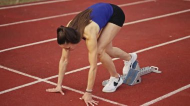 Atletizm atletizm sprint yarışı koşucusu koyu bir arka planda, stadyumun pistinde spor ayakkabılarla koşu koşusuna çıkıyor. Yavaş çekim