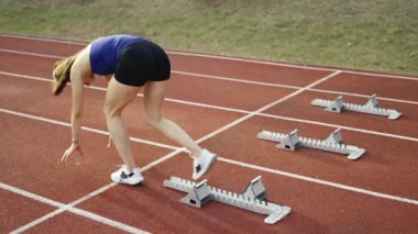 Atletizm atletizm sprint yarışı koşucusu koyu bir arka planda, stadyumun pistinde spor ayakkabılarla koşu koşusuna çıkıyor. Yavaş çekim
