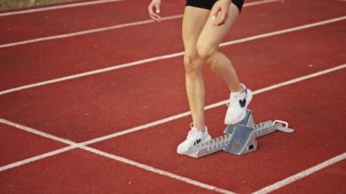 Atletizm atletizm sprint yarışı koşucusu koyu bir arka planda, stadyumun pistinde spor ayakkabılarla koşu koşusuna çıkıyor. Yavaş çekim