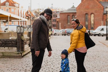 Parents walking hand in hand with their son through the charming city streets, enjoying the warmth of the season and creating joyful memories together clipart