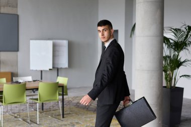 A determined businessman in a black suit confidently walks through the office, embodying professionalism and focus as he heads towards new challenges.  clipart