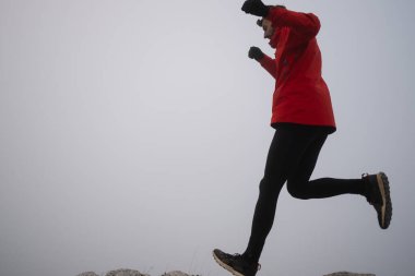 Gökyüzü koşuyor ya da bir dağın tepesinde egzersiz yapan bir kadını takip ediyor. Açık havada antrenman yapan koşucu bir kadın aktif ve zinde bir hayat sürüyor. Siluet sabahın erken saatlerinde.