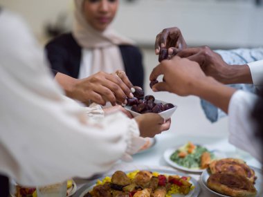 A woman in a hijab extends a platter of dates to her diverse family, creating a scene of unity and joy as they come together to break their fast during the holy month of Ramadan, symbolizing the clipart