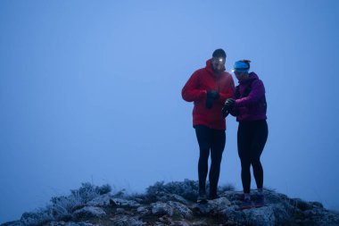 Eğitimden sonra nefes almaktan sıkılan koşucular, teknoloji sporu saatlerine bakmaktan, kalp atış hızı verilerini ve navigasyonlarını kontrol etmekten bıktılar. İki sporcu bir dağda birlikte koşuyor..