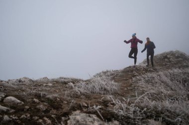 Sabahın erken saatlerinde dağın tepesinde koşan atlet çift patikası. Gökyüzü koşma konsepti, arka planda gökyüzü varken sınırda koşmak tehlikeli. Sağlıklı yaşam, kardiyo egzersizi, spor.