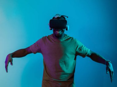 African American man dons VR glasses, engrossed in a virtual reality simulation, gesturing with hands, against a striking blue background, highlighting the fusion of cutting-edge technology and clipart