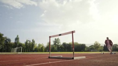 İş adamı atletizm pistinde koşarken engelden atlıyor. Yüksek kalite 4 bin yavaş çekim görüntüsü