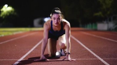 Atletizm atletizm sprint yarışı koşucusu koyu bir arka planda, stadyumun pistinde spor ayakkabılarla koşu koşusuna çıkıyor. Yavaş çekim