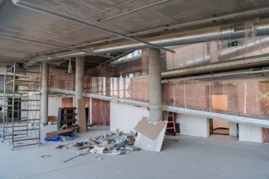 Yapım aşamasındaki modern bir iş binasının büyüleyici bir görüntüsü, çiğ endüstriyel iç mekânını, gün batımının sıcak, altın sarısı renkleri ile yıkanmış çelik kirişleri ve beton duvarlarıyla sergiliyor.. 